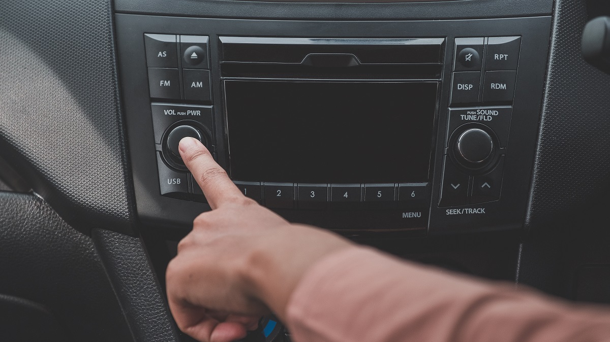 Woman hand turn on the radio on car for listening to music.a